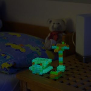 Gebautes Bauwerk aus Leuchtspielsteinen leuchtet im dunklen Kinderzimmer