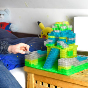 Kind baut eine große Burg aus Leuchtspielsteinen auf einer Bauplatte