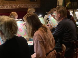 Gäste malen beim MalPub-Abend an Staffeleien