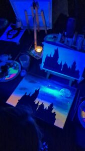 Gemalte Skyline leuchtet beim Malabend unter Schwarzlicht